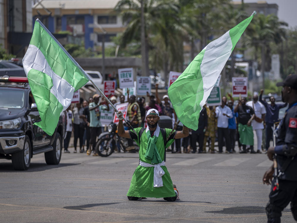 A demonstrator holds two Nigerian flags as he and others accusing the election commission of irregularities and disenfranchising voters make a protest in downtown Abuja, Nigeria.