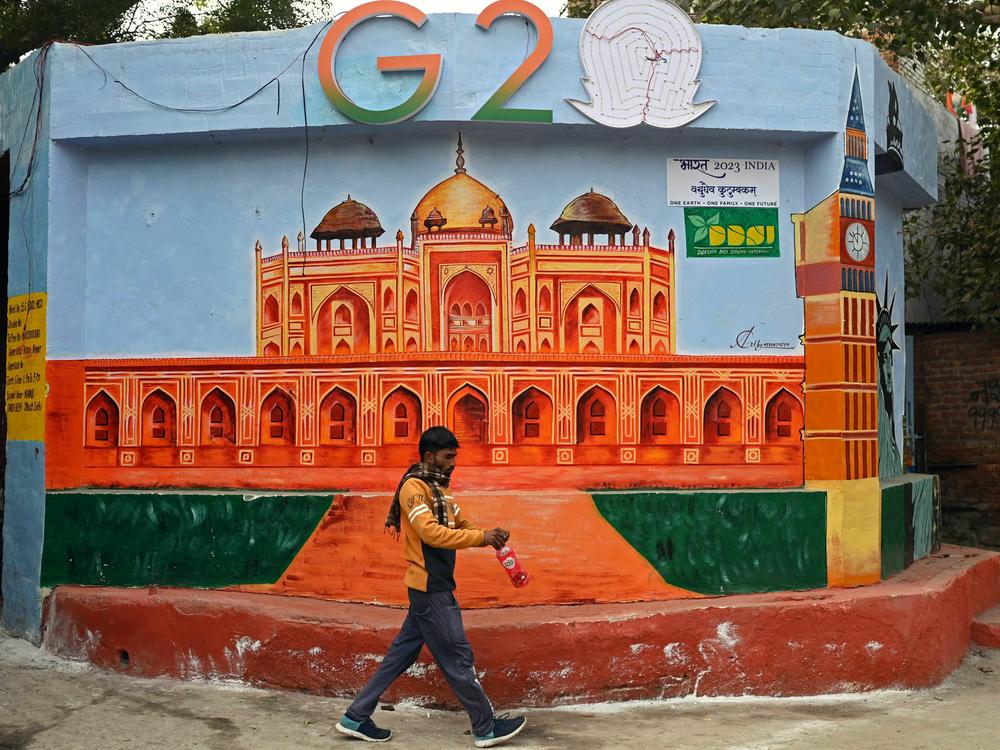 A man walks past a wall mural of Humayun's Tomb under the logo of the Group of 20 summit, in New Delhi on Jan. 4.