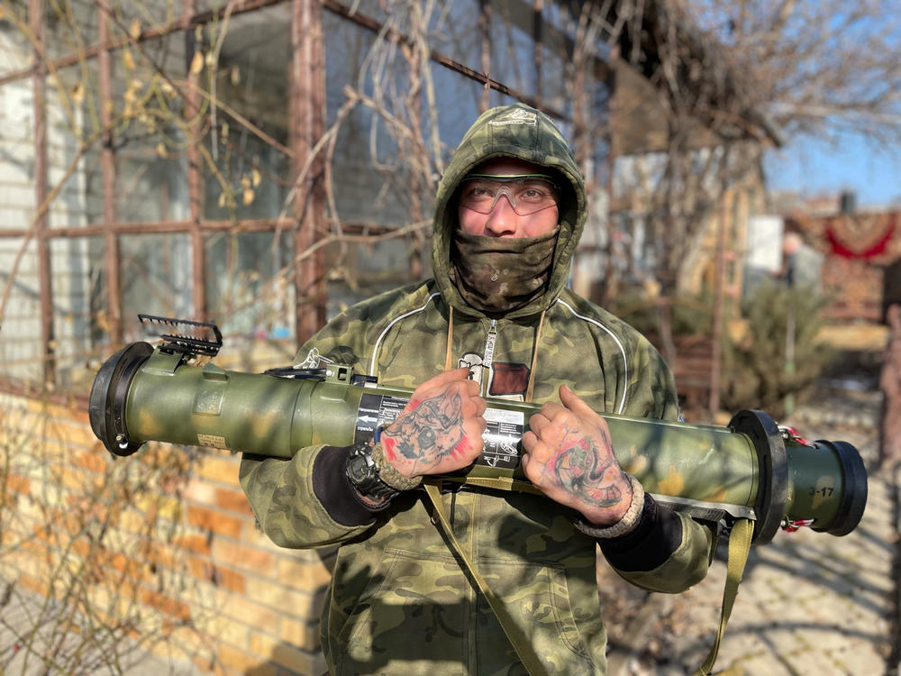 Max, 33, a Ukrainian sniper, poses in the backyard of the reconnaissance team's safe house in the eastern Ukrainian city of Kramatorsk. He's holding a 