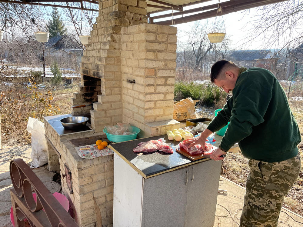 A reconnaissance team member prepares breakfast in the backyard of a safe house the morning after a nighttime trench-clearing operation.