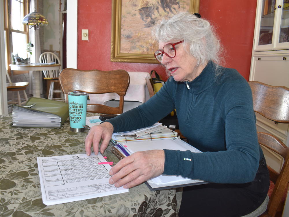 Jennifer Mitchell thumbs through her husband's medical records from his time at the Montana State Hospital. Records show doctors took Mitchell's husband off some of his congestive heart failure medications. Mitchell says she was never consulted.