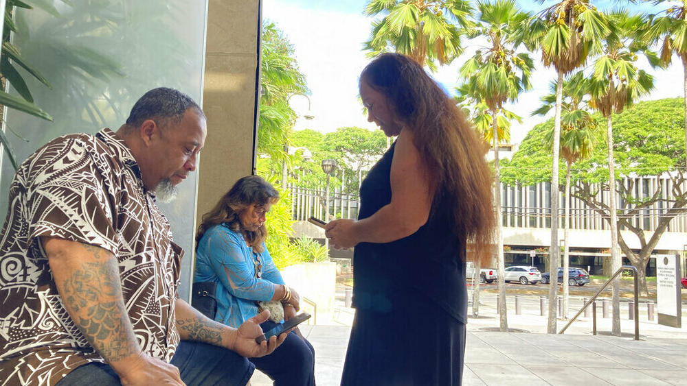 Chico Kaonohi (from eft) prays with Priscilla Hoʻopiʻi and Lana Vierra in November 2022 outside U.S. District Court in Honolulu, after his Native Hawaiian son was found guilty of a hate crime in the 2014 beating of a white man.