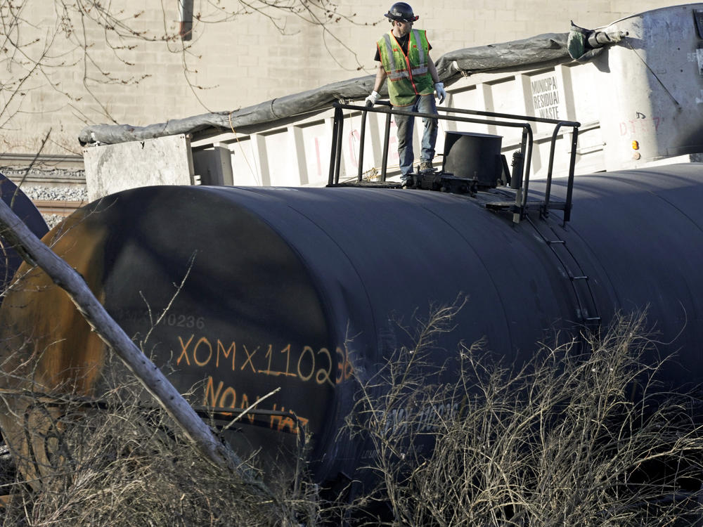 A cleanup worker stands on a derailed tank car of a Norfolk Southern freight train in East Palestine, Ohio, continues, Feb. 15, 2023.