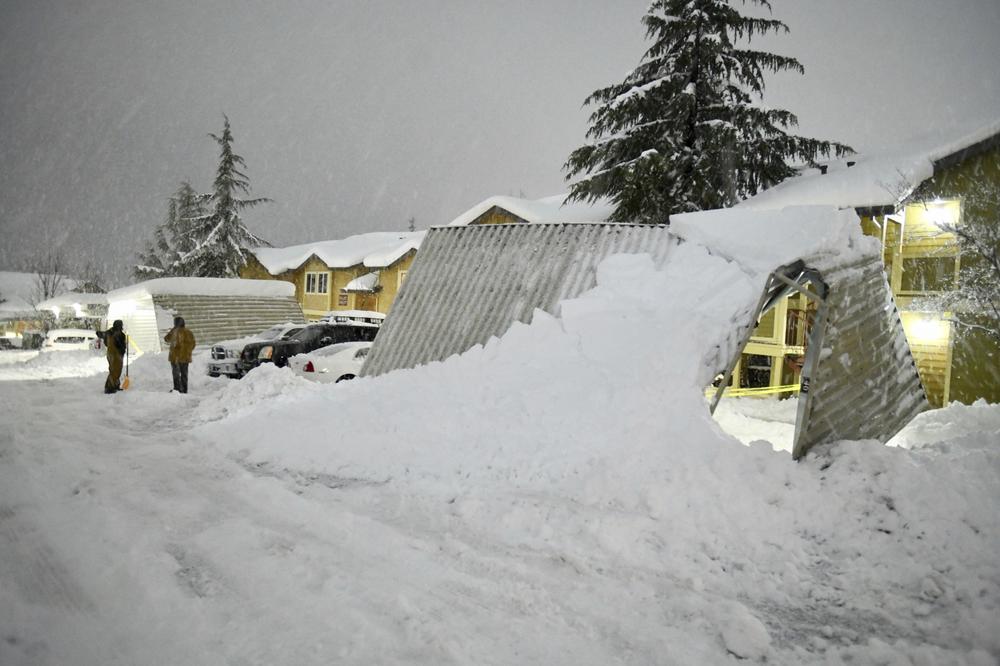 A pair of residents at the Cedar Park apartments in Grass Valley, Calif., take a break from shoveling snow during blizzard conditions on Feb. 28, 2023.
