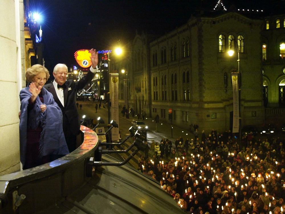 December 10, 2002: Nobel Peace Prize winner, former US President Jimmy Carter (2ndL) and his wife Rosalynn (L), greet wellwishers during a torchlight procession, from the balcony of Grand Hotel in downtown Oslo, prior the Norwegian Nobel Committee's banquet.