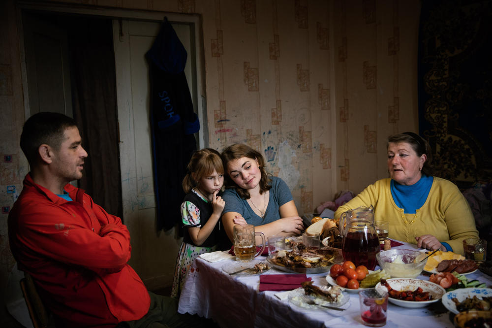 Left to right: Dmytro Drobysh, his wife Hanna, their daughter Angelina and neighbor Olena Dovhozhenko eat lunch in Poltava region. The Drobysh family are part of the Grinik's extended family and the reason they came here when Russia invaded. December 2022.