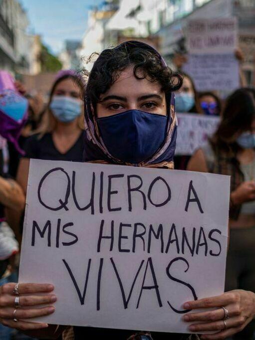 A member of a feminist collective holds a sign that reads in 