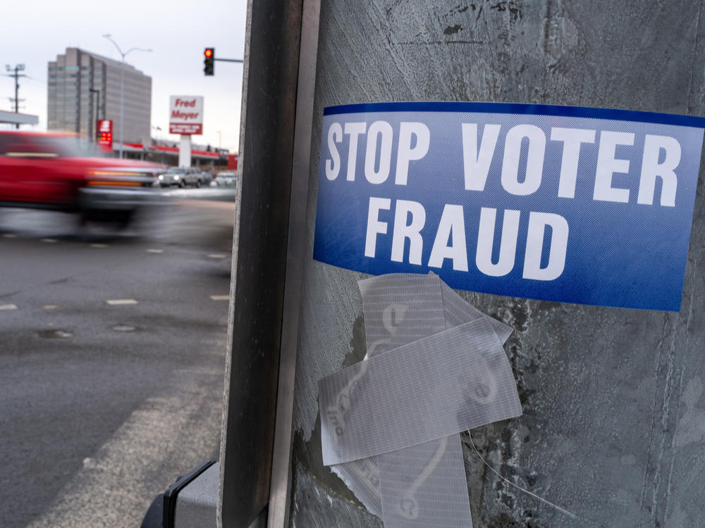 A sticker on a lamp post warns of voter fraud on Nov. 7, 2022, in Anchorage, Alaska. Alaska is part of a bipartisan compact of more than 30 states that shares voting data.