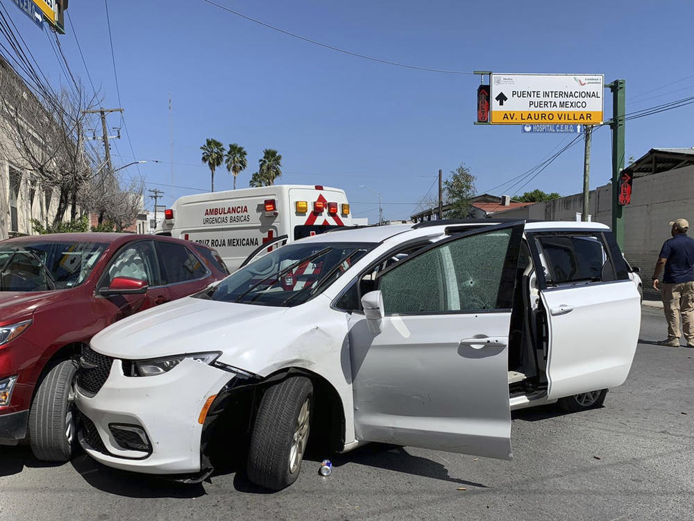 A member of the Mexican security forces stands next to a white minivan with North Carolina plates and several bullet holes at the scene of the crime in Matamoros on Friday.