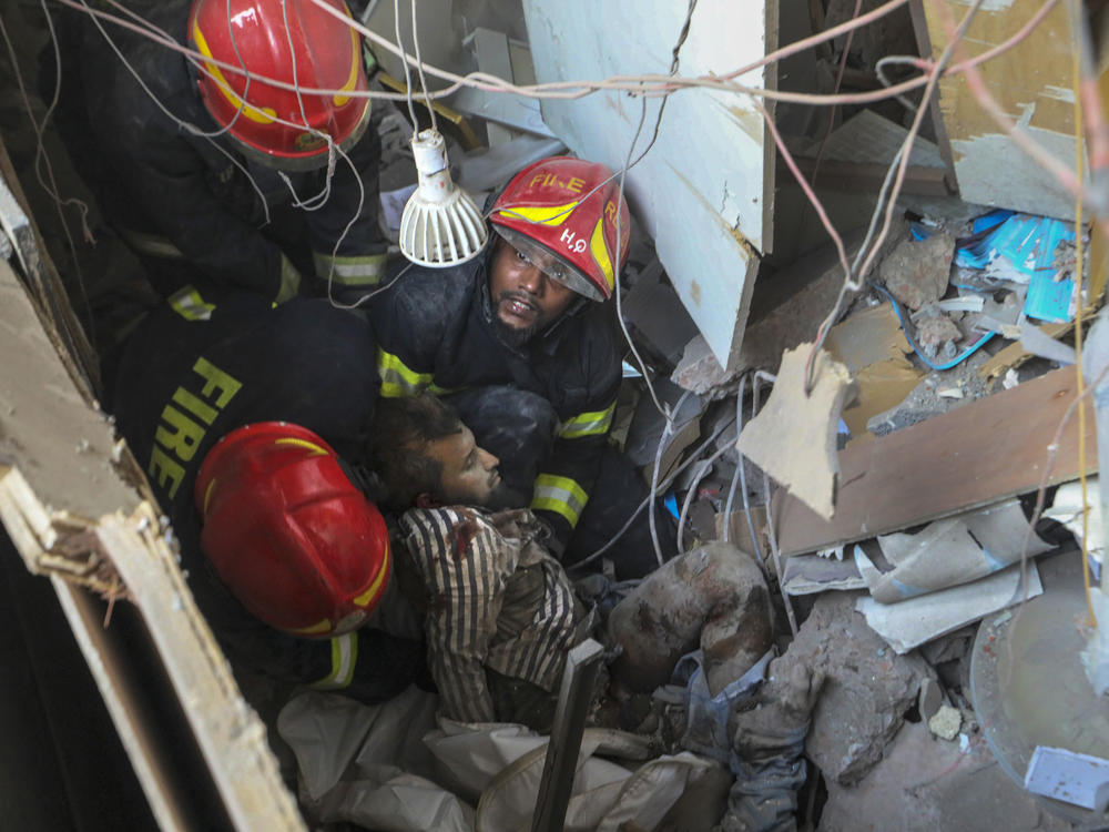 Fire officials rescue an injured person from the debris of a commercial building after an explosion, in Dhaka, Bangladesh, Tuesday.