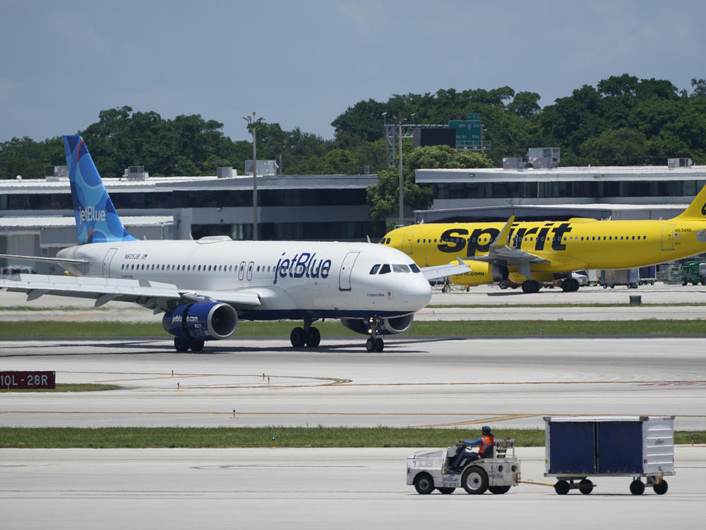 A JetBlue Airways Airbus A320 (left) passes a Spirit Airlines Airbus A320 as it taxis on the runway on July 7, 2022, at the Fort Lauderdale-Hollywood International Airport in Fort Lauderdale, Fla. The Biden administration wants to block JetBlue from buying Spirit, saying the deal would reduce competition and hurt travelers.