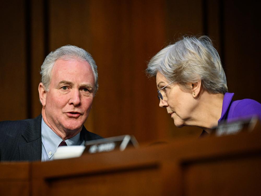 Sen. Chris Van Hollen, Dem-Md., talks to Sen. Elizabeth Warren, Dem-Mass., during the Senate Banking Committee hearing with Powell on Capitol Hill in Washington, D.C., on Tuesday. Warren pressed Powell on job losses that could result from the Fed's aggressive interest rate hikes.