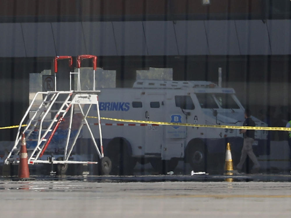 Photographed through a fence, an armored truck is surrounded by police tape at the Arturo Merino Benitez International Airport in Santiago, Chile, on Wednesday. An airport shootout killed a security officer and an alleged robber in what authorities say was an attempted heist of more than $32 million in cash aboard a plane from Miami.