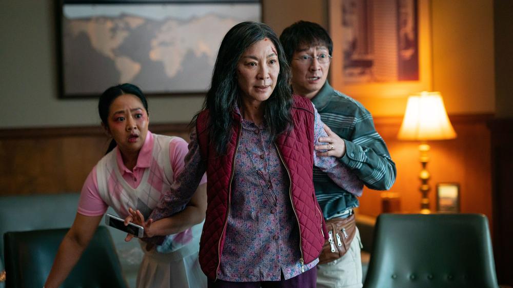 Michelle Yeoh (center) plays Evelyn Wang, a Chinese immigrant who owns a failing laundromat. She protects her daughter Joy (left), played by Stephanie Hsu, and her husband Waymond (right), played by Ke Huy Quan.