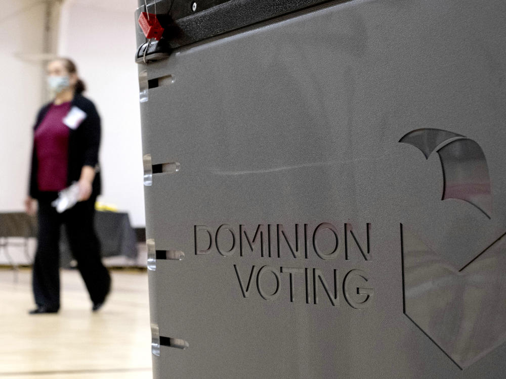 In this 2021 file photo, a Georgia poll worker passes a Dominion Voting Systems ballot scanner. Dominion, which has been the subject of conspiracy theories since the 2020 election, was recently ditched by officials in California's Shasta County.