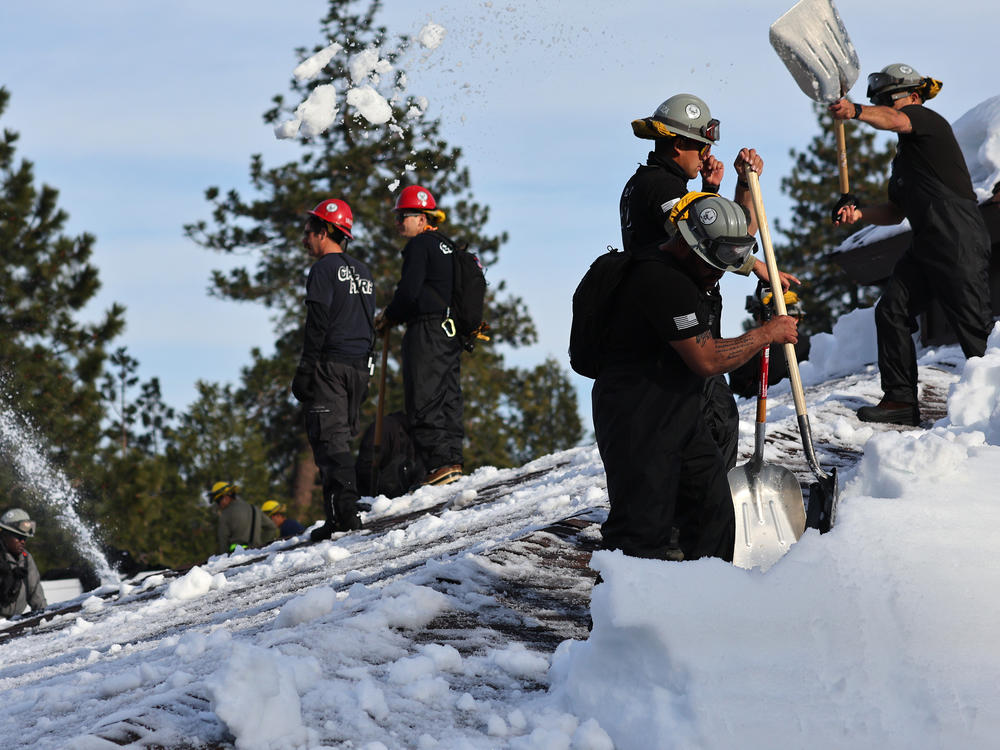Members of the California Army National Guard Joint Task Force Rattlesnake shovel snow from a rooftop after a series of winter storms dropped more than 100 inches of snow in the San Bernardino Mountains in Southern California on March 8, 2023 in Crestline, California.