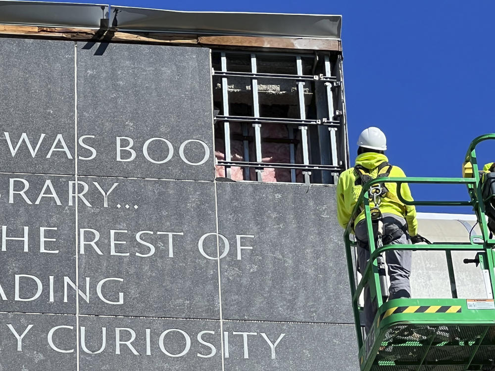 Workers remove a partial quote by Malcolm X from the facade of the main library at the University of Rhode Island in Kingston, R.I..