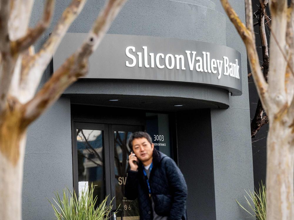 A pedestrian speaks on a mobile telephone as he walks past Silicon Valley Bank's headquarters in Santa Clara, Calif., on Friday after a run on deposits made it no longer tenable for the bank to stay afloat on its own.