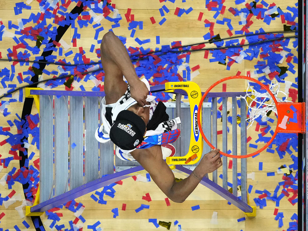 David McCormack of the Kansas Jayhawks cuts down the net after defeating the North Carolina Tar Heels in March Madness last year.