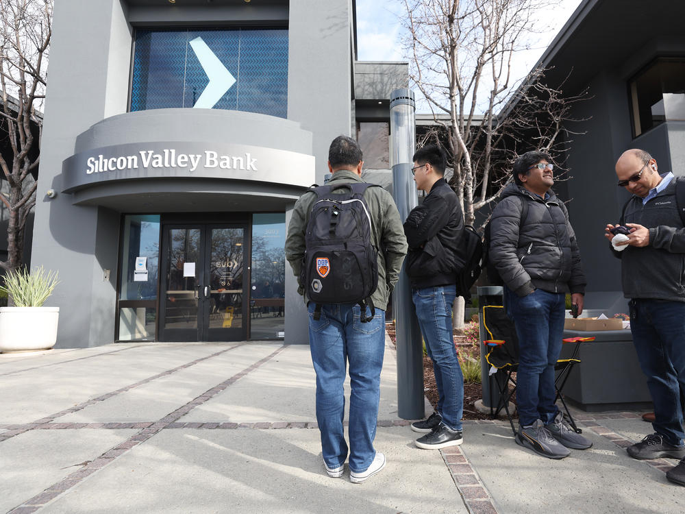 People line up outside of a Silicon Valley Bank office on Monday in Santa Clara, Calif. Days after Silicon Valley Bank collapsed, customers are lining up to try and retrieve their funds from the failed bank.
