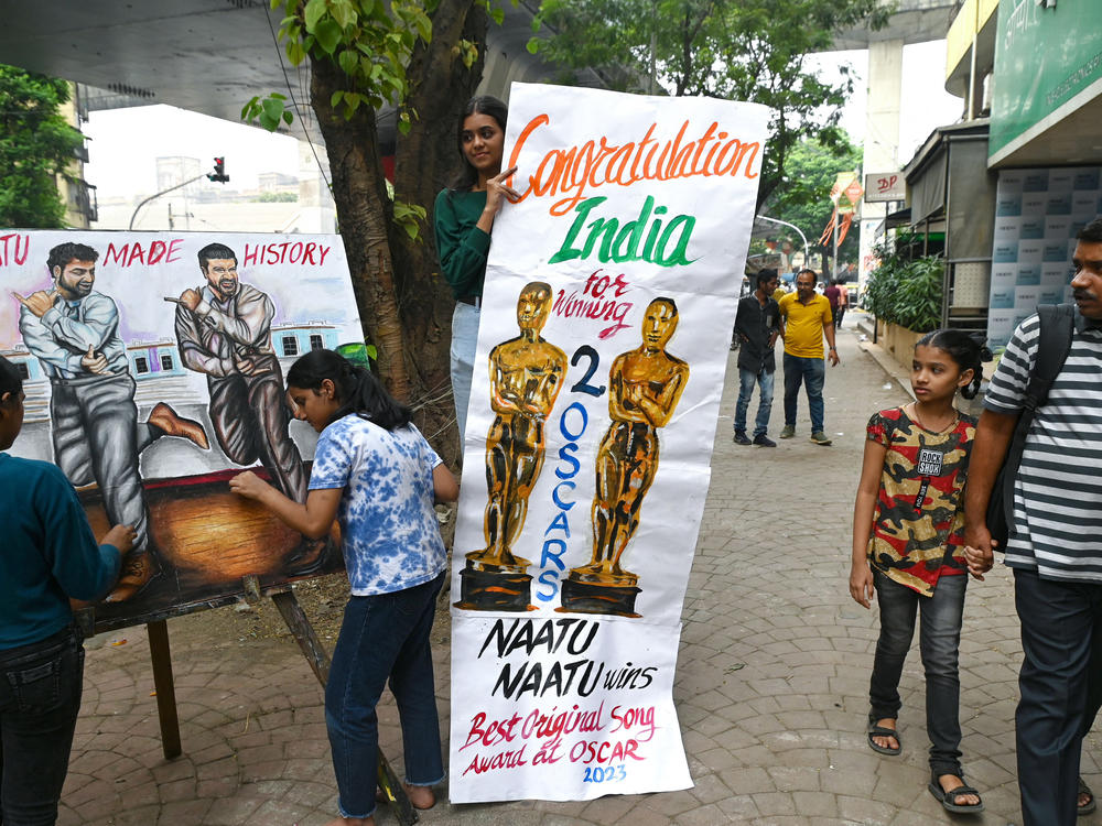 Art school students in Mumbai finish up a painting of Indian actors N.T. Rama Rao Jr. (left) and Ram Charan of the movie <em>RRR</em>, whose dance song 