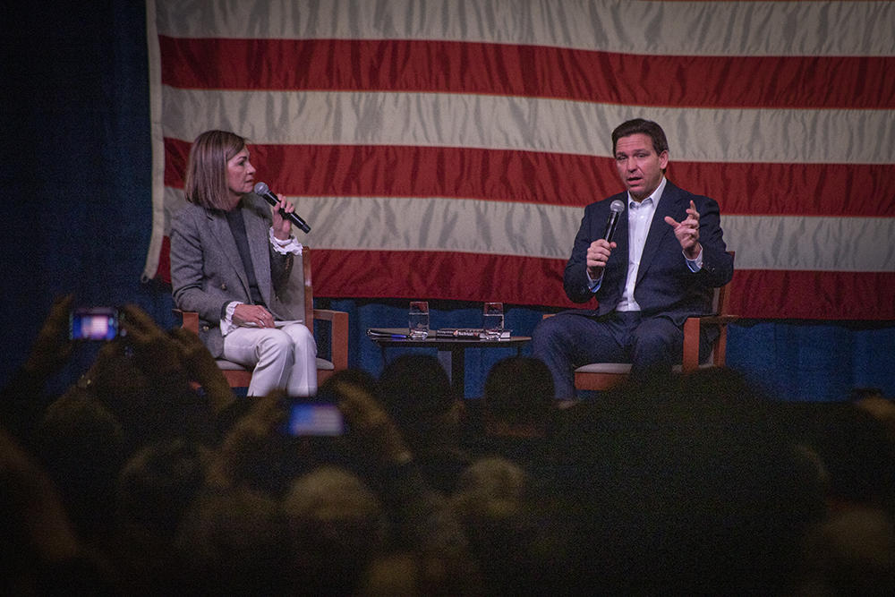 Florida Gov. Ron DeSantis talks with Iowa Gov. Kim Reynolds during a trip to Davenport, Iowa, on March 10, while he mulls a run for president in 2024.