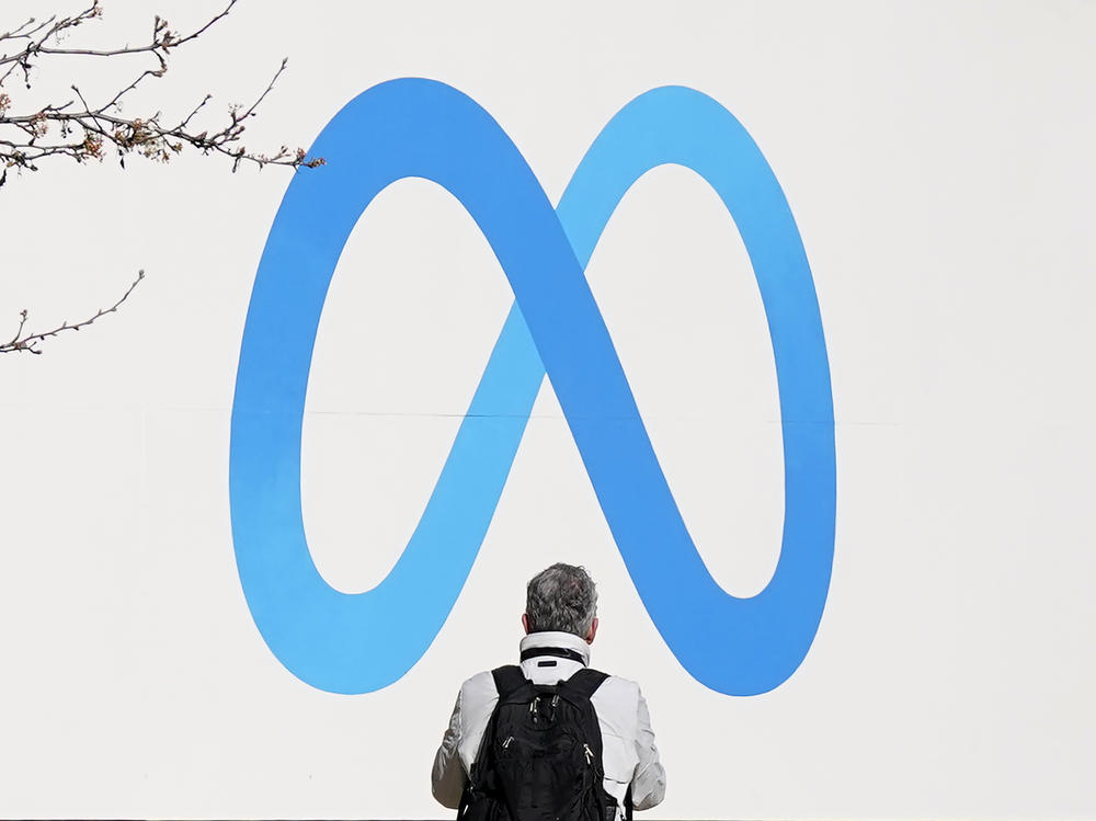 A person stands in front of a Meta sign outside of the company's headquarters in Menlo Park, Calif. on March 7.