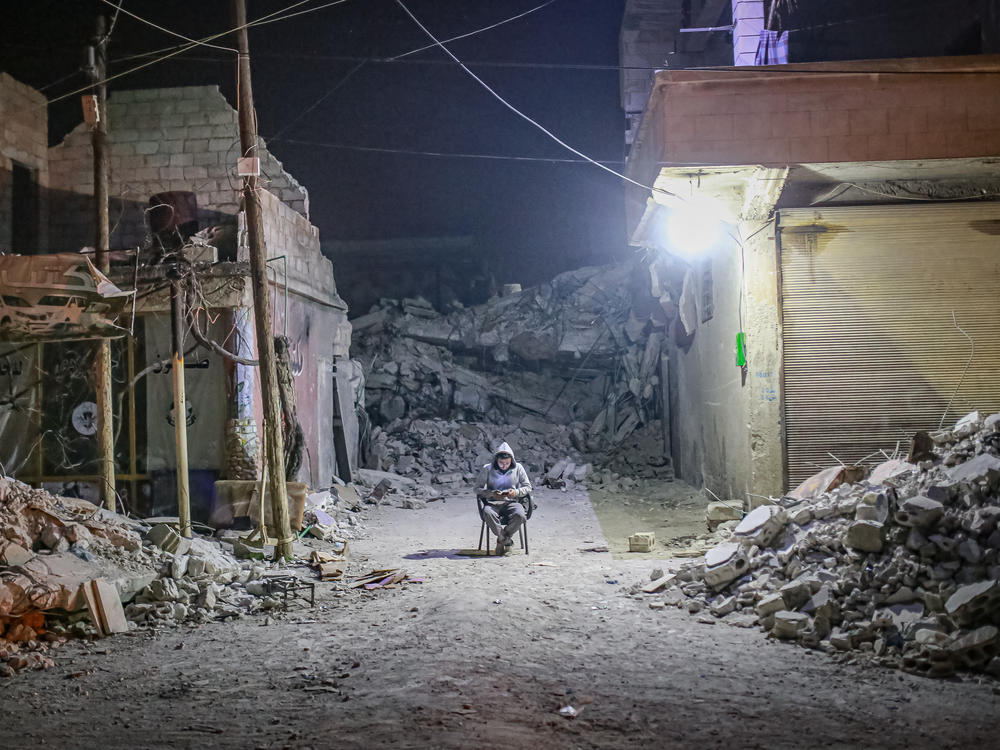 A quake survivor spends a night outside in Idlib, Syria on Feb. 9, 2023, following 7.7 and 7.6 magnitude earthquakes centered in neighboring Turkey. A doctor in Syria says it's still difficult to get needed medical supplies.