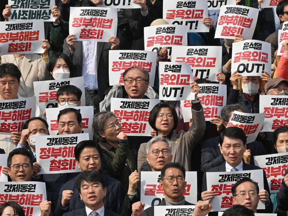 South Korean lawmakers and protesters hold placards during an anti-government rally denouncing South Korea's plans to compensate victims of Japan's forced wartime labor, at the National Assembly in Seoul on March 7. Seoul hopes a new plan to compensate victims may help end a historic dispute with Tokyo.