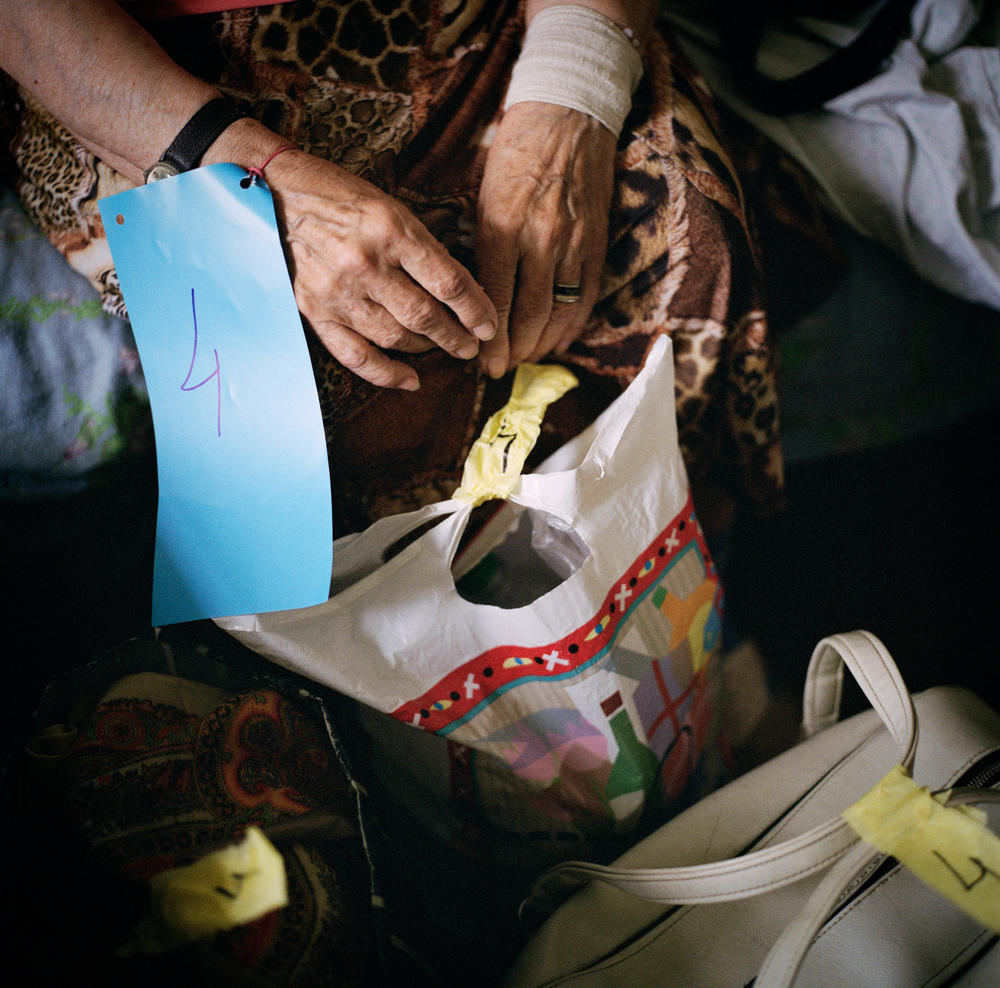 The Ukrainian Red Cross prepares a patient for medical evacuation from Sloviansk hospital. To keep track of evacuees and their belongings, everyone is issued a numbered tag that matches the patient's luggage. June 2022.