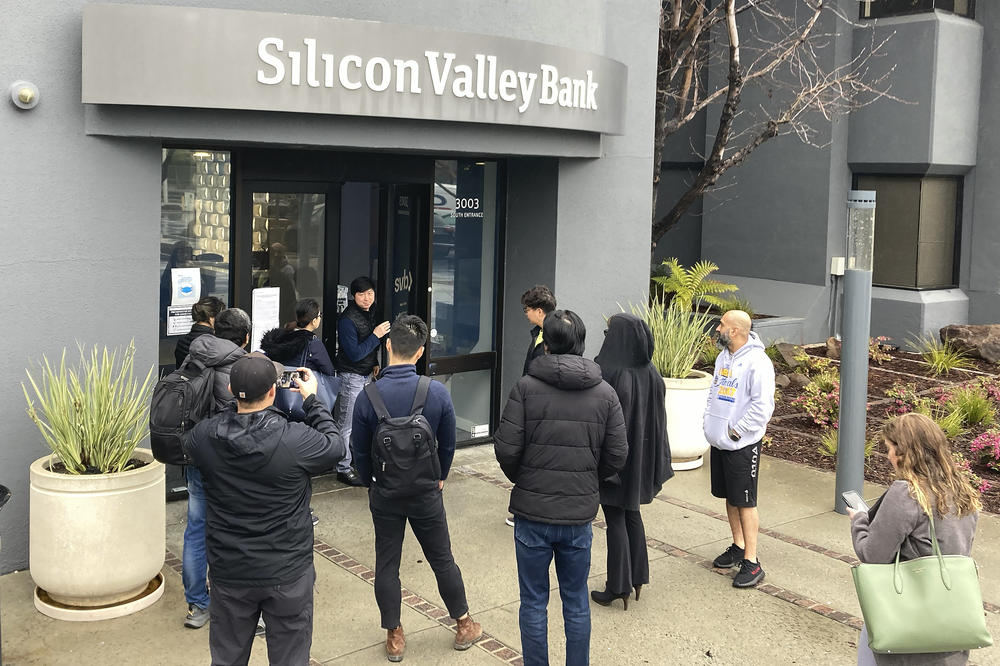 A person talks to people waiting outside of an entrance to Silicon Valley Bank in Santa Clara, Calif. on March 10.