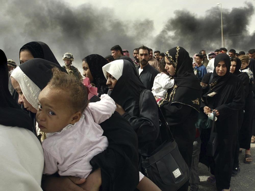 March 30, 2003: Women line up for a security check by British soldiers on the outskirts of Basra, as they try to flee from this southern Iraqi town.