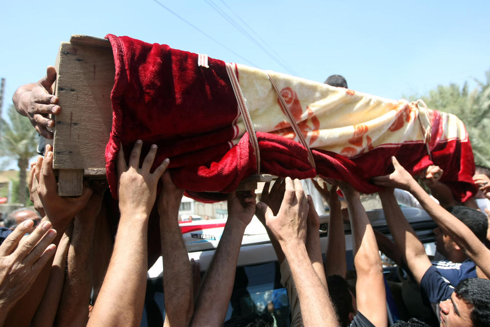 April 25, 2010: Iraqi men carry the coffin of one of the victims of a triple bombing attack outside a mortuary in the Baghdad.