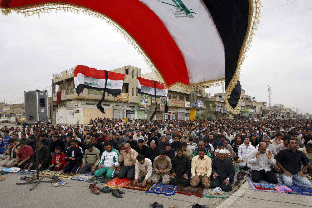 Nov. 28, 2009: Iraq's flag flutters in the wind as Iraqi Shia take part in Friday noon prayers in Sadr City.