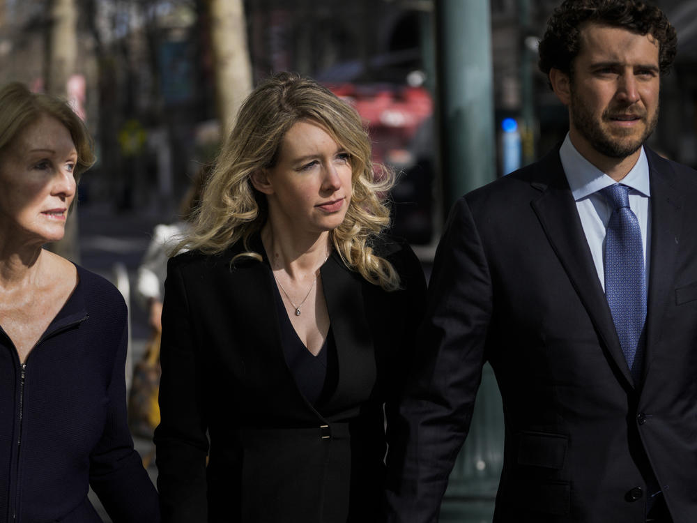 Former Theranos CEO Elizabeth Holmes, center, walks into court in San Jose, Calif., on Friday alongside her mother, Noel Holmes, and partner, Billy Evans.
