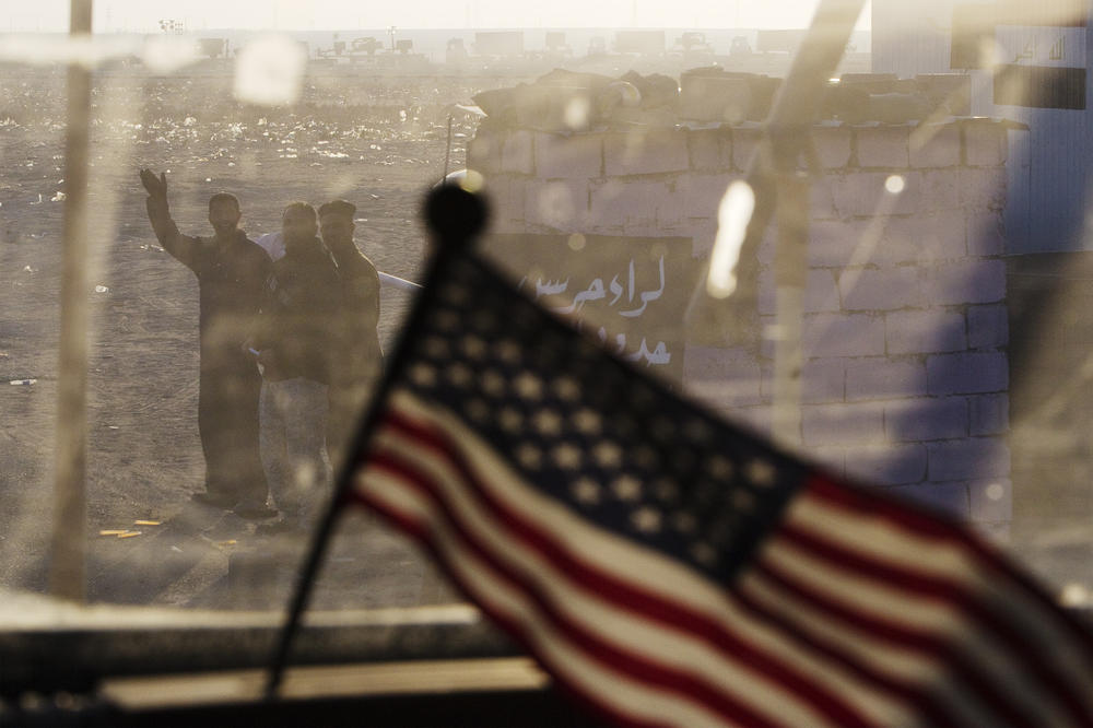 Dec. 18, 2011: Iraqis wave behind a U.S. flag on the dashboard of a Mine-Resistant Ambush-Protected (MRAP) vehicle that's part of the 3rd Brigade Combat Team's 1st Cavalry Division, as part of the last U.S. military convoy to leave Iraq near Nasiriyah, Iraq.