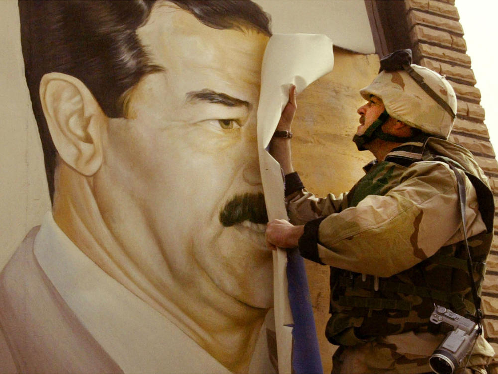 U.S. Marine Maj. Bull Gurfein pulls down a poster of Iraqi President Saddam Hussein on March 21, 2003, a day after the start of the U.S. invasion, in Safwan, Iraq.