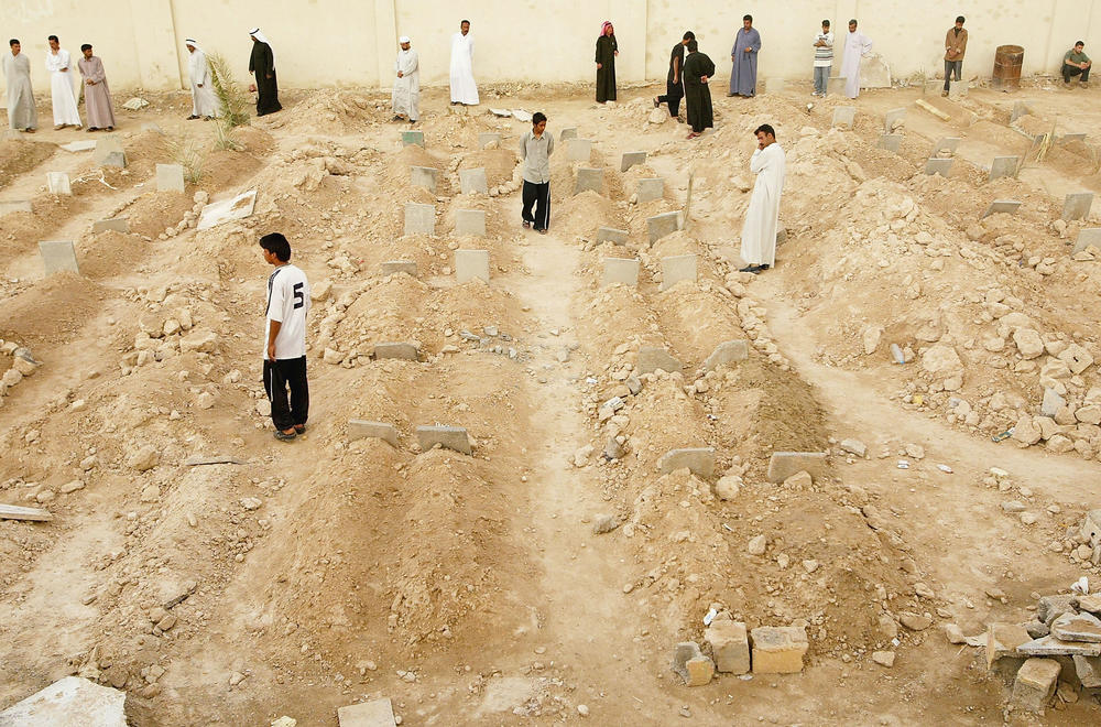 May 3, 2004: People look at rows of graves at an overflowing cemetery built in a soccer arena, in Fallujah, Iraq. An estimated 1,300 Iraqis had been killed in the monthlong siege of Fallujah, and the death toll continued to rise as residents returned home to find more bodies.