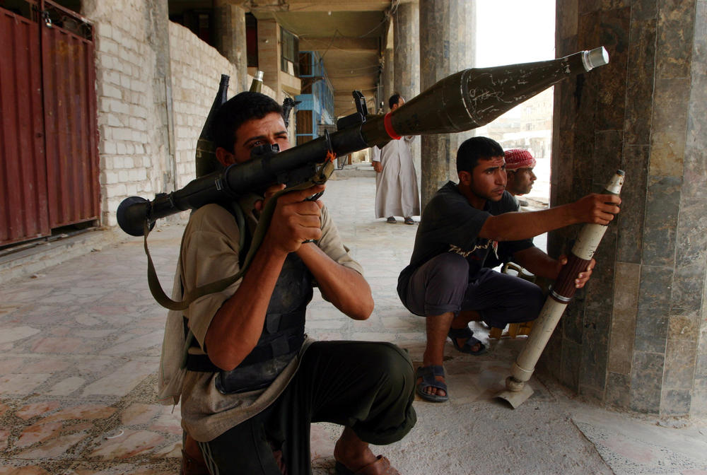 Aug. 7, 2004: Iraqi Shia militiamen prepare to fire their weapons during clashes with U.S. Marines in Najaf, Iraq.