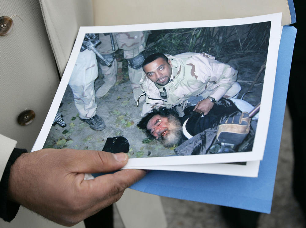 A photo of the capture of Saddam Hussein, subdued during his capture.