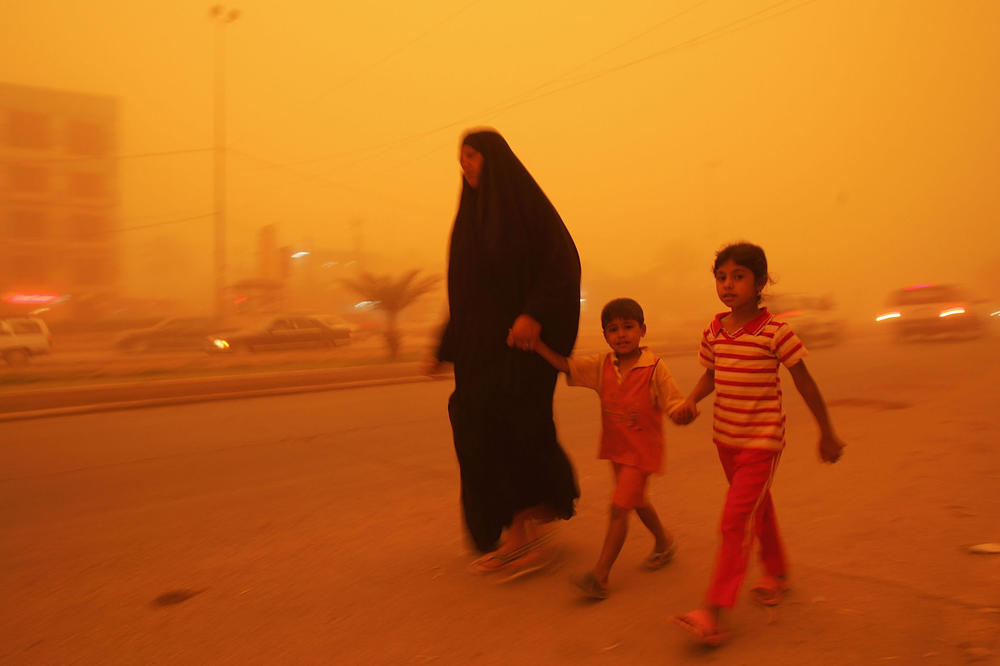 April 27, 2008: A woman walks with her children during a sandstorm in Baghdad.