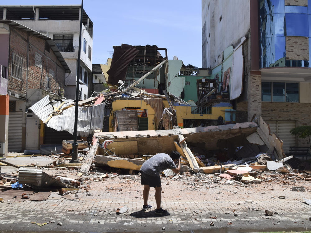 A man takes a photo of a building that collapsed after an earthquake shook Machala, Ecuador, on Saturday.