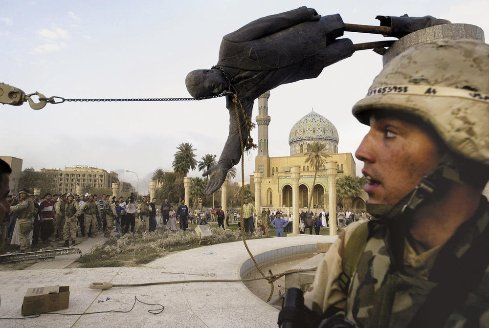 Iraqi civilians and U.S. soldiers pull down a statue of Saddam Hussein in downtown Baghdad, April 9, 2003.