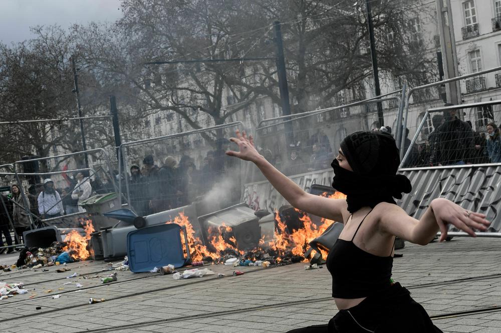 A woman poses by a burning barricade during a demonstration in Nantes on March 18.