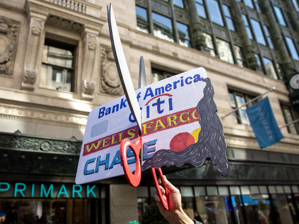 A protester in Boston holds up a large replica of a credit card being cut in half during a national day of action to 