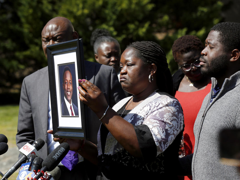 Caroline Ouko holds a portrait of her son, Irvo Otieno, as attorney Ben Crump (left) and her older son, Leon Ochieng (right) look on at the Dinwiddie Courthouse in Dinwiddie, Va., on Thursday.