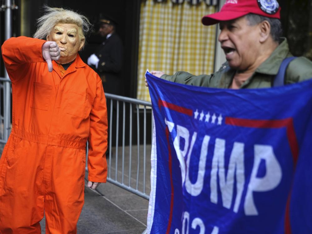 Mike Hisey, left, wearing a mask of former President Donald Trump in a prison uniform while Mariano Laboy, right, holds a Trump reelection sign outside of Trump Tower on Tuesday  in New York.