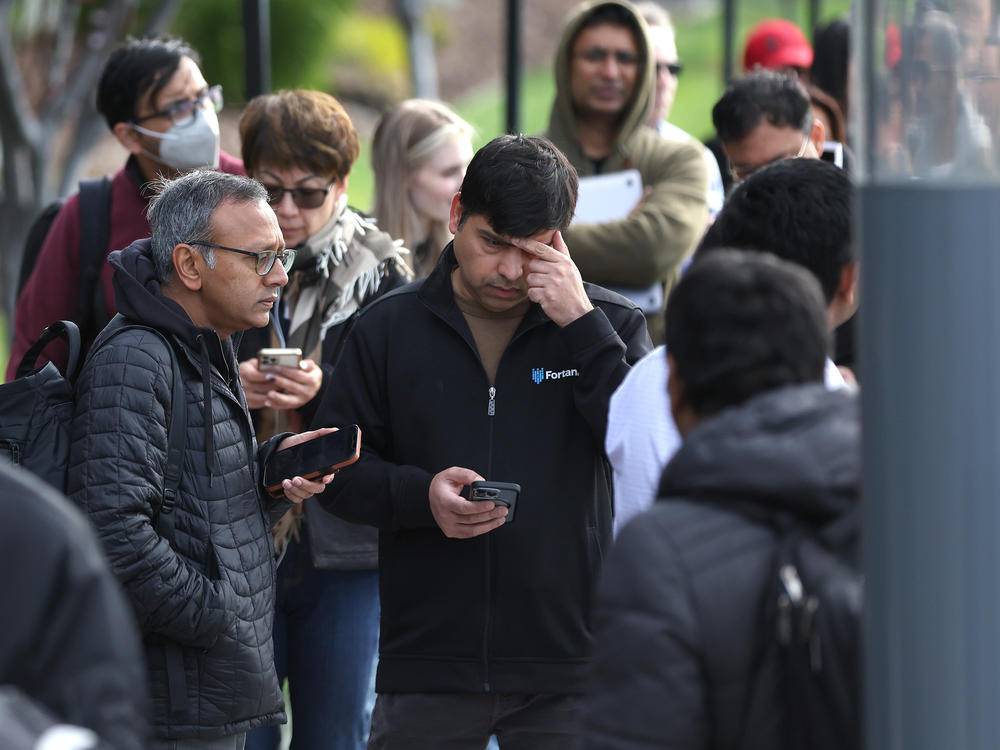 People line up outside of a Silicon Valley Bank office in Santa Clara, Calif., on March 13, 2023, the day after regulators swept in to protect depositors at the failed lender. Despite the emergency action, panicked depositors sought to withdraw money from smaller and regional lenders.