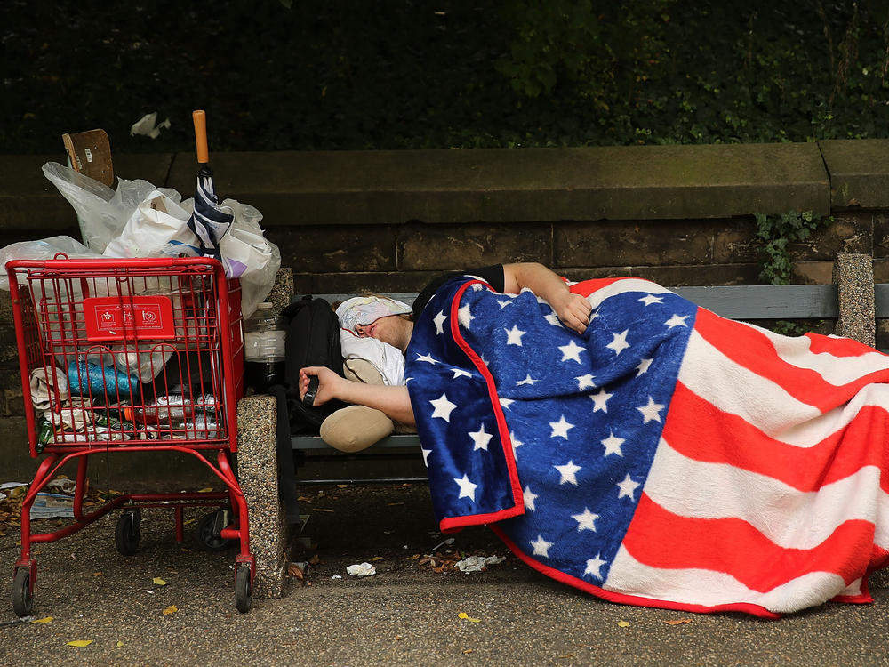 An unhoused individual sleeps under an American flag blanket in New York City on Sept. 10, 2013. In 2021, approximately 11% of Americans lived below the federal poverty line.