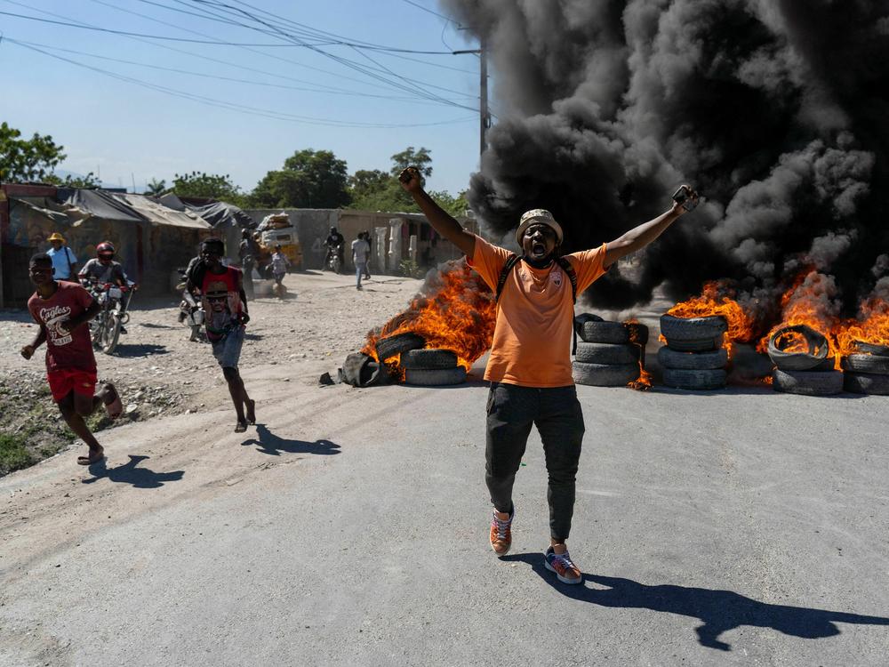 A man gestures and shouts by a burning tires barricade during a police demonstration after a gang attack on a police station which left six officers dead, in Port-au-Prince, Haiti, January 26, 2023.